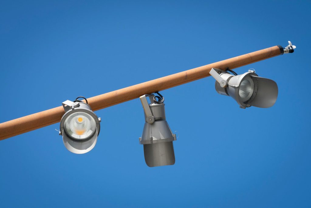 Three spotlights on a pole with a blue sky in the background